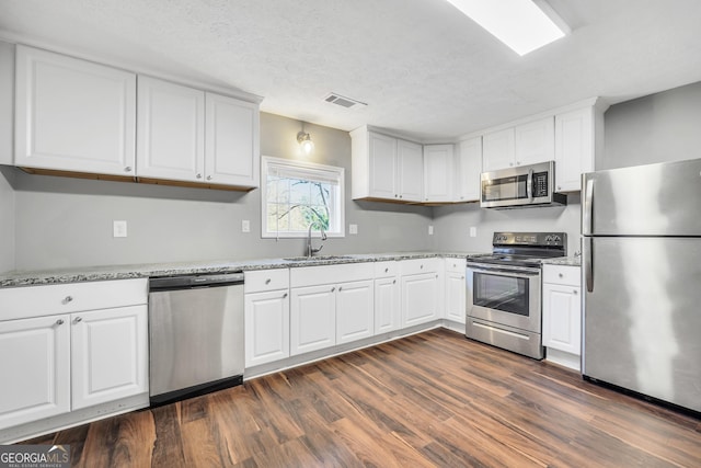 kitchen featuring light stone countertops, stainless steel appliances, sink, white cabinets, and dark hardwood / wood-style floors