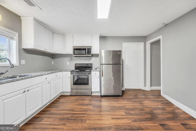 kitchen with white cabinetry, sink, light stone countertops, and appliances with stainless steel finishes