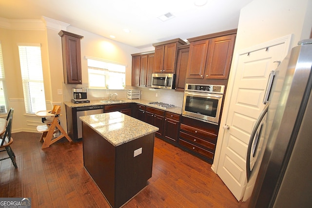 kitchen featuring appliances with stainless steel finishes, a kitchen island, dark wood-type flooring, and sink