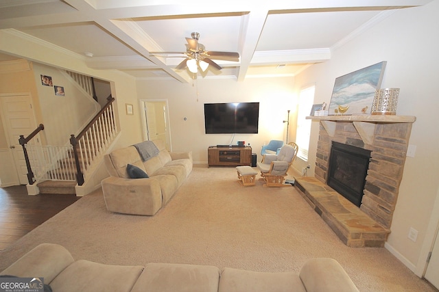 carpeted living room featuring coffered ceiling, a stone fireplace, ceiling fan, ornamental molding, and beamed ceiling