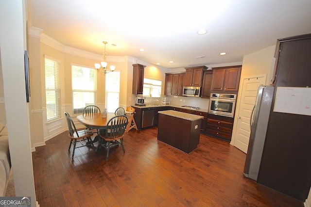 kitchen with stainless steel appliances, pendant lighting, a notable chandelier, a center island, and dark hardwood / wood-style floors