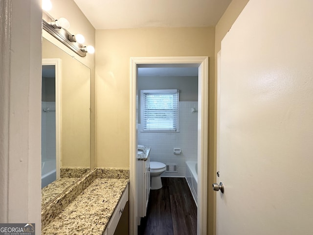 bathroom with vanity, wood-type flooring, tile walls, and toilet