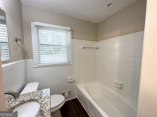 bathroom with hardwood / wood-style flooring, vanity, toilet, and tile walls