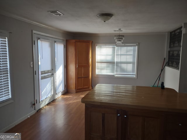 unfurnished dining area featuring wood-type flooring, ornamental molding, and a chandelier