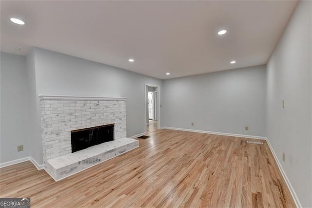 unfurnished living room with light hardwood / wood-style floors and a brick fireplace