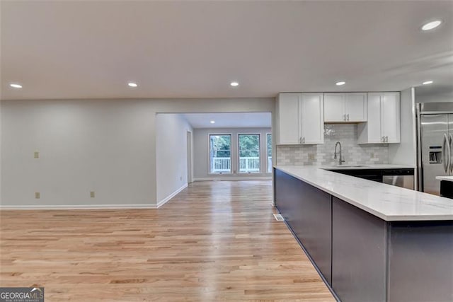 kitchen with white cabinetry, sink, light stone countertops, built in fridge, and decorative backsplash