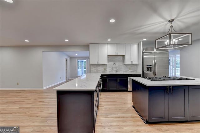 kitchen featuring hanging light fixtures, stainless steel fridge with ice dispenser, a notable chandelier, light stone counters, and white cabinetry