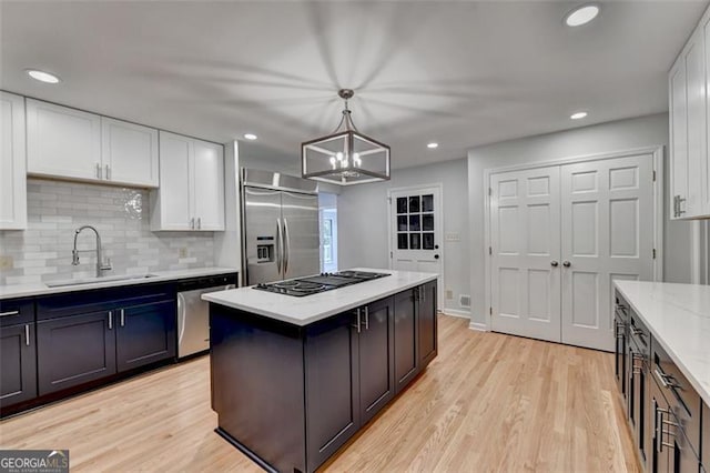 kitchen featuring light stone countertops, white cabinetry, sink, pendant lighting, and appliances with stainless steel finishes