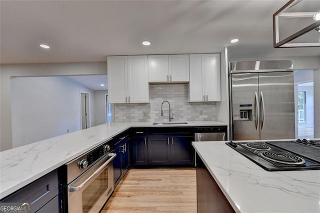 kitchen featuring light stone countertops, white cabinetry, sink, and stainless steel appliances