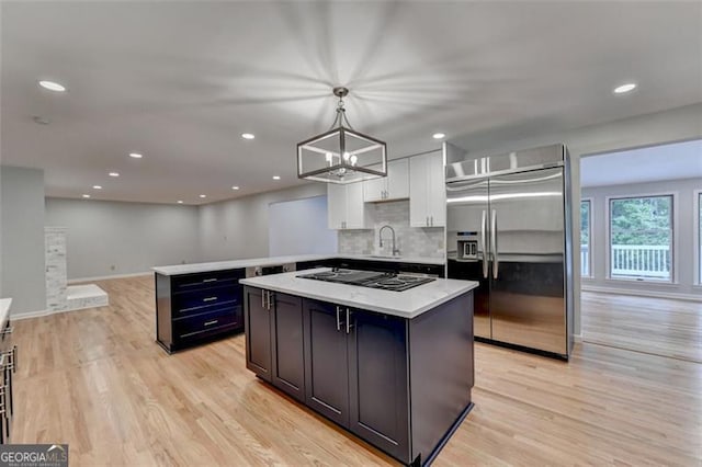 kitchen featuring built in fridge, a kitchen island, white cabinets, and hanging light fixtures