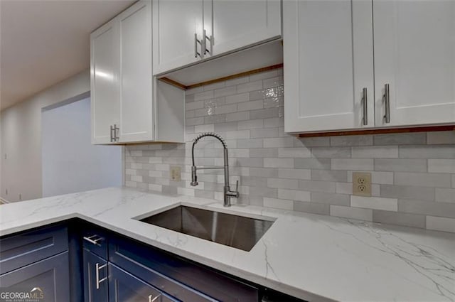 kitchen with white cabinets, decorative backsplash, sink, and blue cabinetry