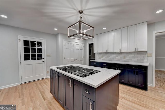 kitchen with white cabinetry, cooktop, tasteful backsplash, a chandelier, and pendant lighting