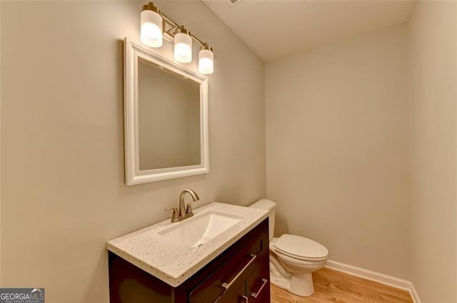 bathroom with hardwood / wood-style flooring, vanity, and toilet