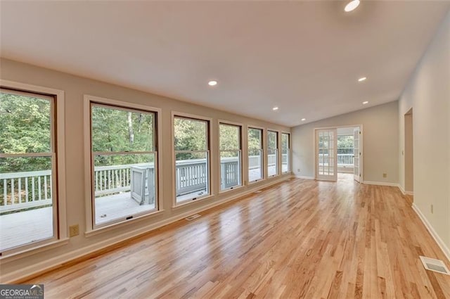 unfurnished living room with plenty of natural light, light hardwood / wood-style floors, and lofted ceiling