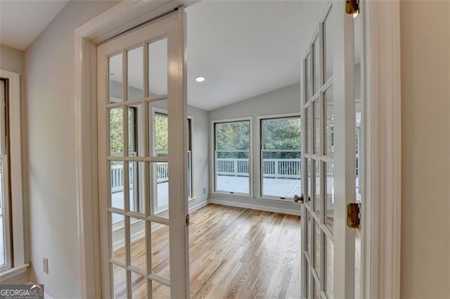 entryway with french doors, light hardwood / wood-style floors, and lofted ceiling