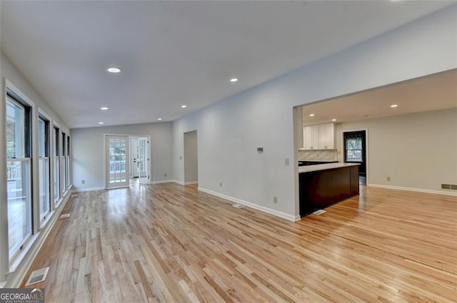 unfurnished living room with plenty of natural light, light hardwood / wood-style floors, and lofted ceiling