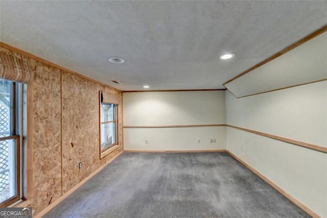 unfurnished room featuring dark colored carpet, lofted ceiling, a healthy amount of sunlight, and ornamental molding