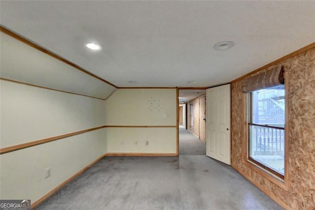 unfurnished room featuring carpet, crown molding, and lofted ceiling