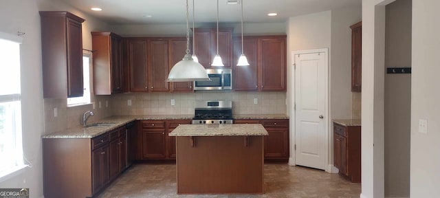 kitchen featuring sink, light stone counters, decorative light fixtures, a kitchen island, and appliances with stainless steel finishes