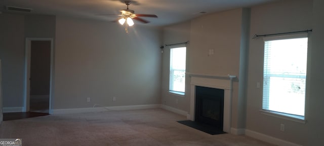 unfurnished living room featuring light carpet, ceiling fan, and a healthy amount of sunlight