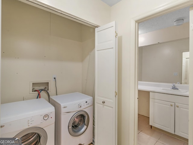 washroom with washing machine and clothes dryer, light tile patterned floors, a textured ceiling, and sink