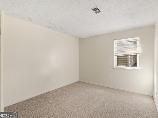 unfurnished room with carpet and a textured ceiling