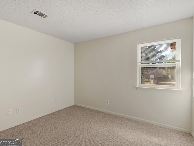 carpeted empty room featuring a textured ceiling