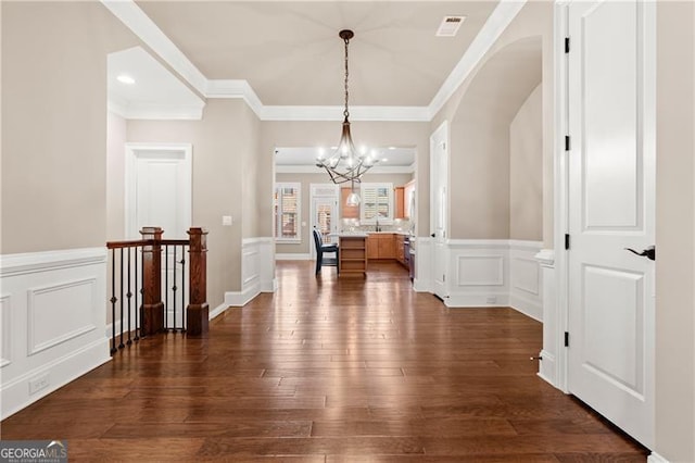 interior space with an inviting chandelier, dark wood-type flooring, and ornamental molding