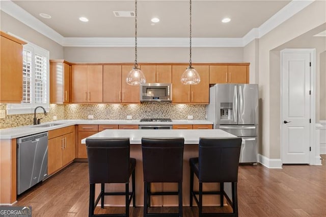 kitchen featuring sink, hanging light fixtures, stainless steel appliances, light brown cabinetry, and a kitchen island