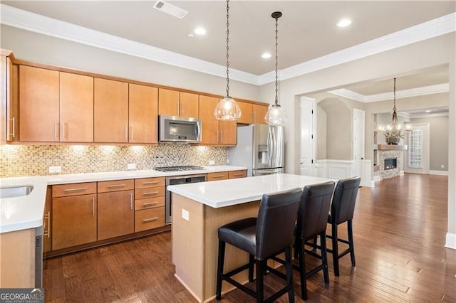 kitchen featuring a kitchen bar, appliances with stainless steel finishes, backsplash, dark wood-type flooring, and a kitchen island