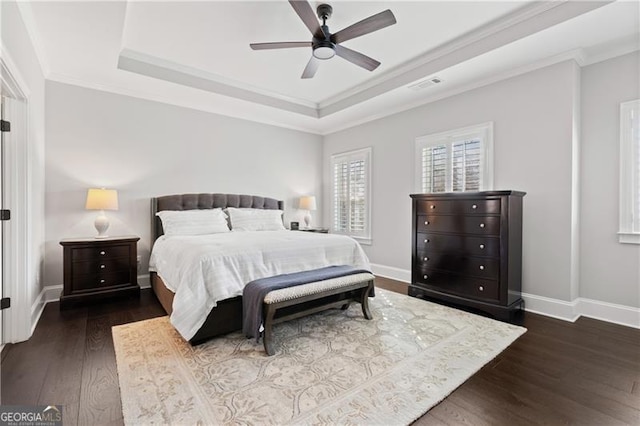 bedroom featuring a tray ceiling, ceiling fan, crown molding, and dark hardwood / wood-style floors