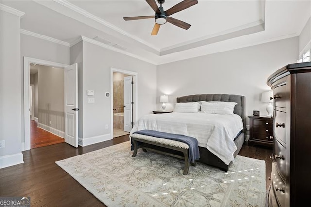 bedroom featuring dark hardwood / wood-style flooring, ensuite bath, a raised ceiling, ceiling fan, and crown molding