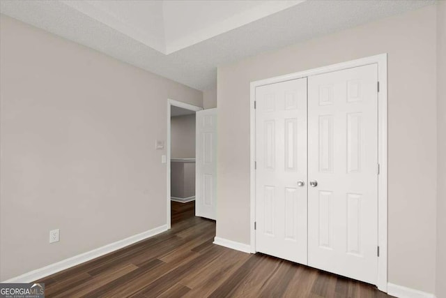 unfurnished bedroom with a closet and dark hardwood / wood-style floors