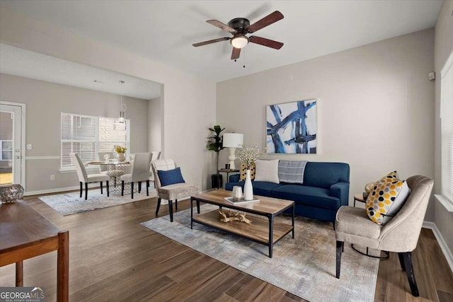 living room with ceiling fan and dark wood-type flooring