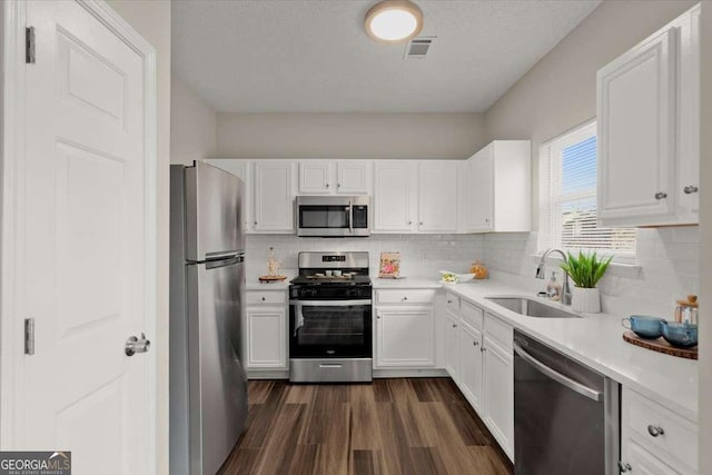 kitchen with dark hardwood / wood-style floors, white cabinetry, sink, and appliances with stainless steel finishes