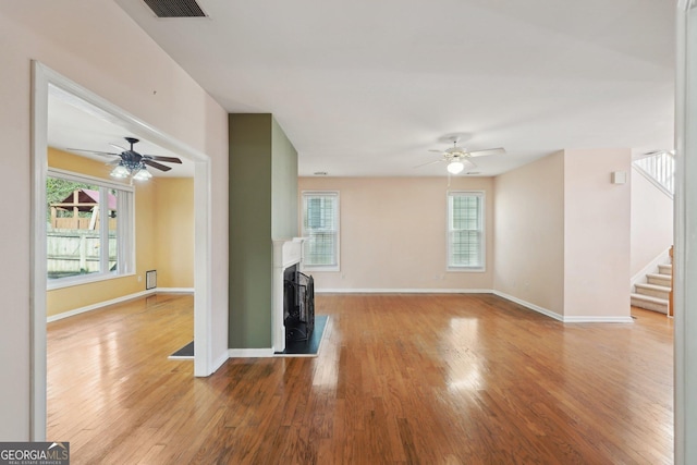 unfurnished living room featuring light wood-style flooring, a fireplace, visible vents, baseboards, and stairs