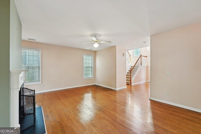 unfurnished living room featuring light wood finished floors, stairway, a fireplace, and baseboards