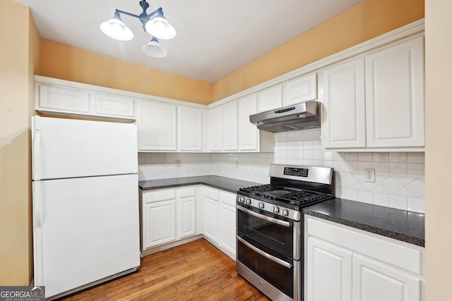 kitchen with white cabinets, dark countertops, freestanding refrigerator, under cabinet range hood, and double oven range