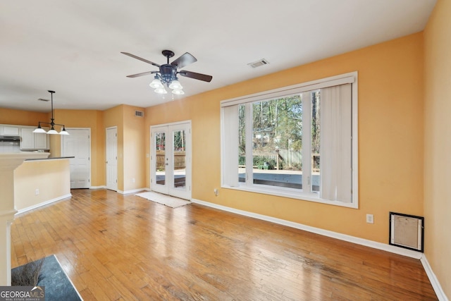 unfurnished living room with french doors, light wood-type flooring, visible vents, and baseboards