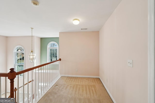 hallway with carpet, visible vents, and baseboards