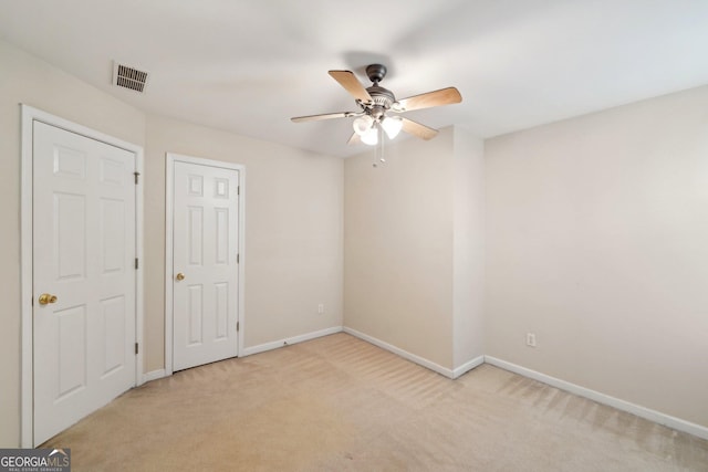 unfurnished bedroom featuring baseboards, a ceiling fan, visible vents, and light colored carpet