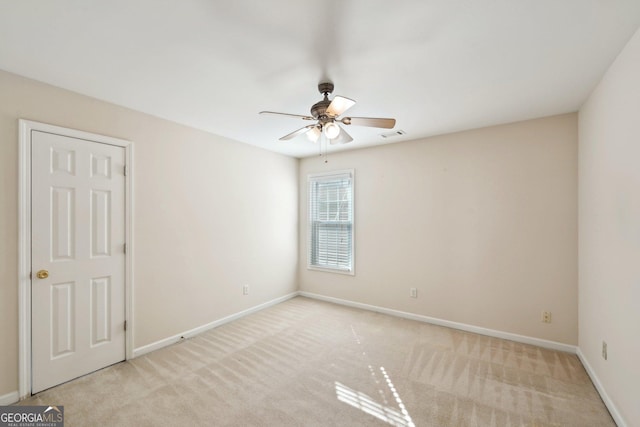 empty room with baseboards, a ceiling fan, visible vents, and light colored carpet