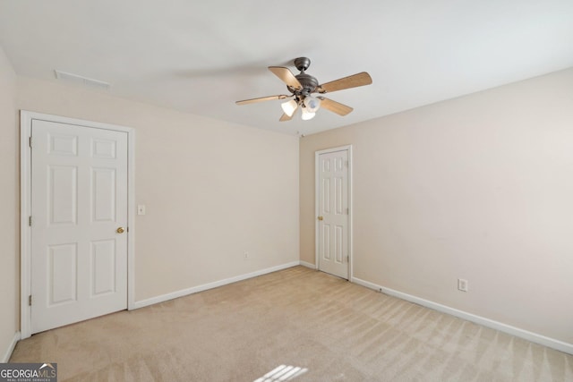 empty room featuring light carpet, ceiling fan, visible vents, and baseboards