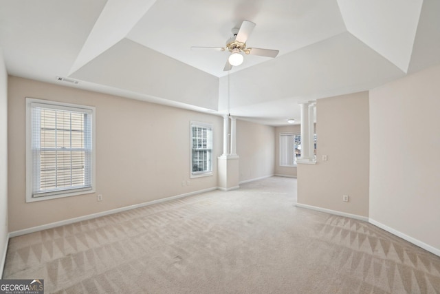 empty room with baseboards, vaulted ceiling, visible vents, and light colored carpet