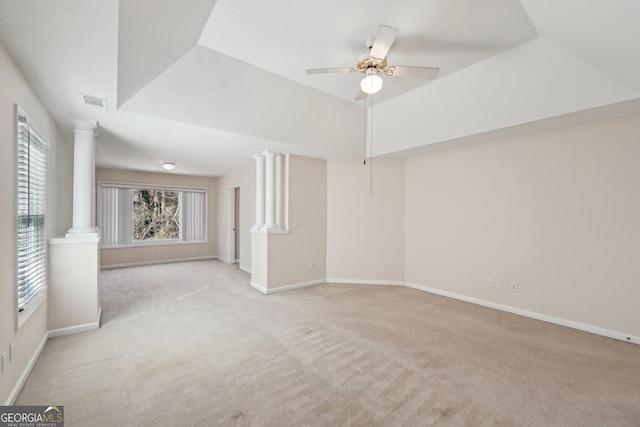 spare room featuring light carpet, baseboards, a raised ceiling, and ornate columns