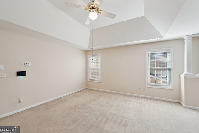 empty room featuring a tray ceiling, light colored carpet, and decorative columns