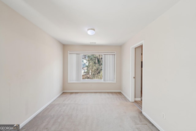 spare room featuring light carpet and baseboards