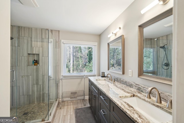 full bath with a sink, a shower stall, and double vanity