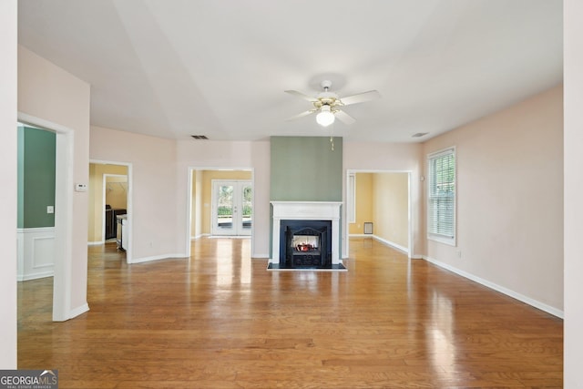 unfurnished living room featuring a fireplace with flush hearth, light wood-type flooring, and a wealth of natural light