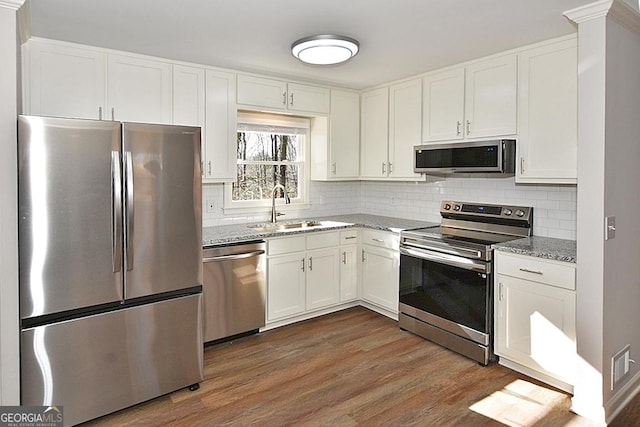 kitchen featuring light stone countertops, stainless steel appliances, white cabinetry, and sink